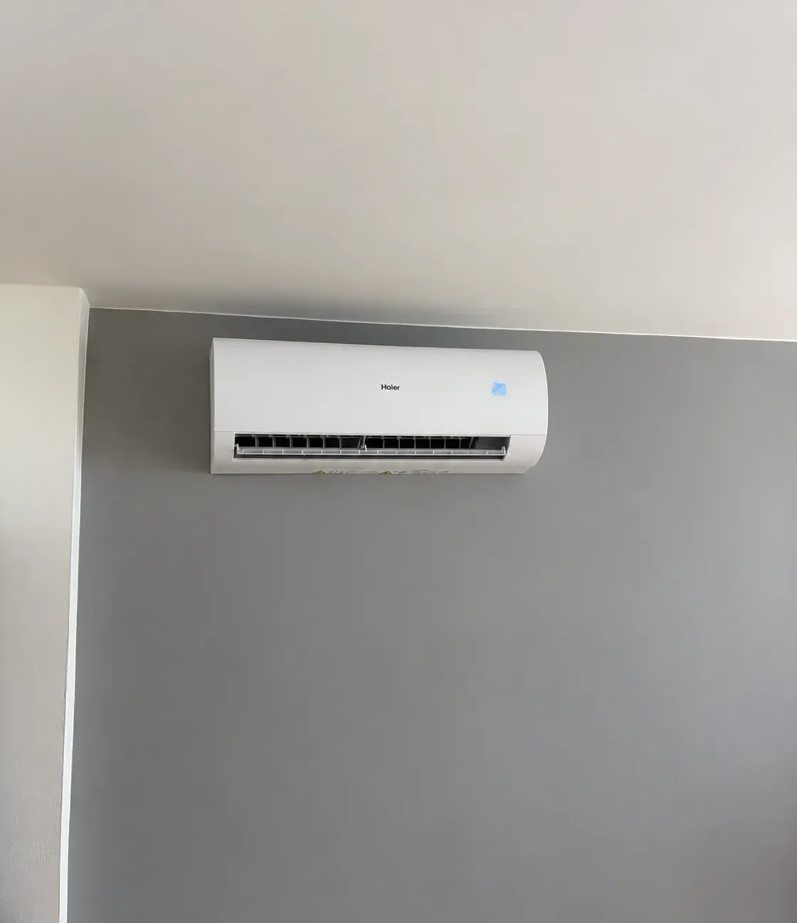 Vnitřní jednotka Haier Pearl Premium pod stropem na šedé stěně